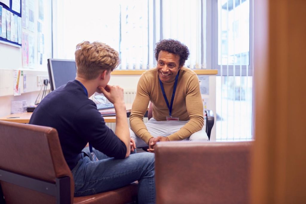 two men sitting down and discussing the benefits of recovery coaching