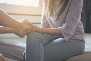 a person holding hands with a woman consoling her during crisis management