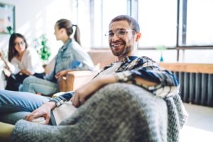 a man smiles at camera while sitting in a group that's discussing what is recovery coaching