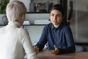 a woman sits with another woman discussing what is financial coaching and how it can help