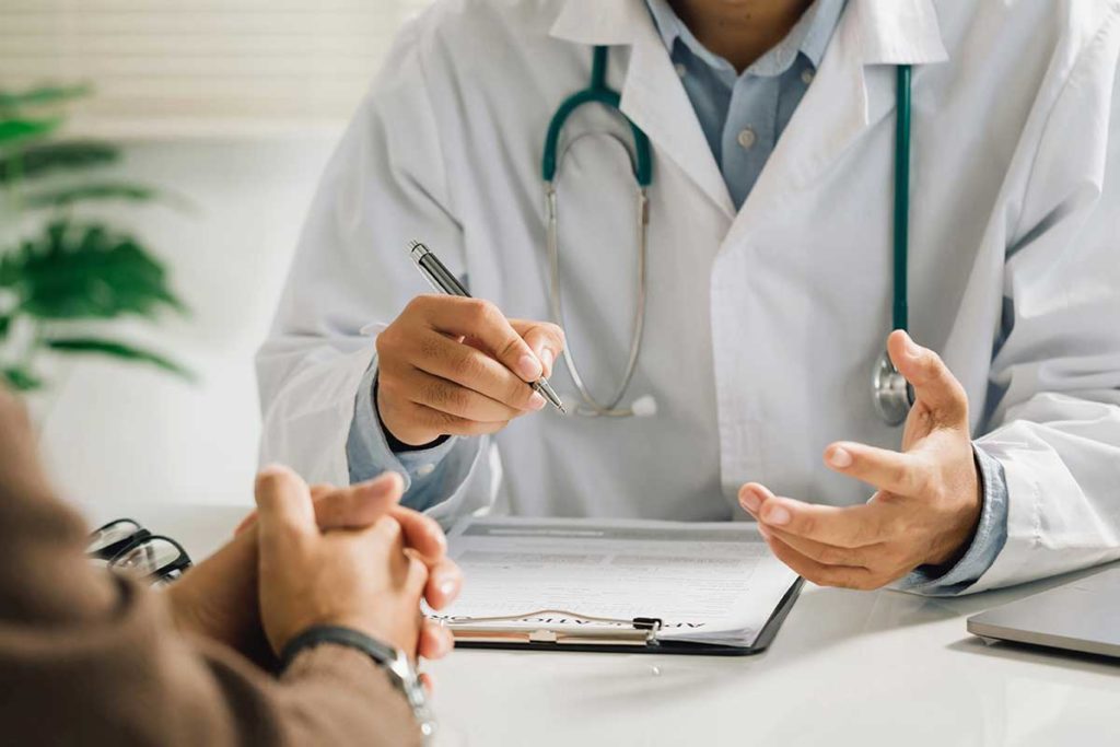 a doctor is listening to a patient and writing down on his clipboard about the crisis standards of care