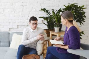 a man sits on the a couch speaking with his therapist about interventions for anxiety and how they could help