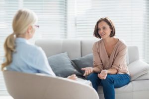 a woman sits with a therapist discussing therapy interventions for anxiety for a family member