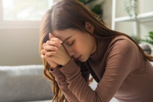 a woman holds her palms to her forehead appearing distraught and dealing with hard times