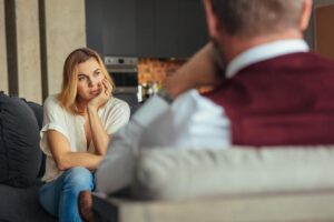 an adult woman sits on a couch with her chin resting on her hand talking to a therapist about what does legal aid help with