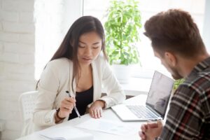 a financial coach sits at desk with a member going through his financial paperwork and creating a plan of action