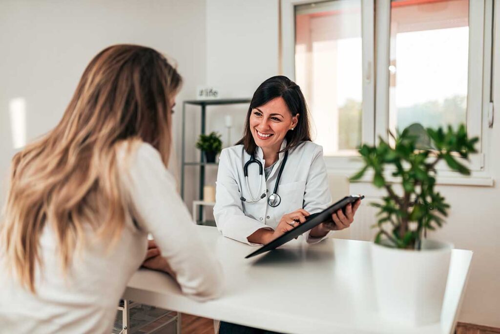 a medical professional sits a table with a patient and shows her some paperwork that discusses the importance of treatment planning