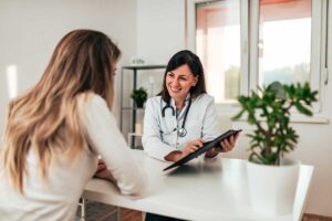 a medical professional sits a table with a patient and shows her some paperwork that discusses the importance of treatment planning