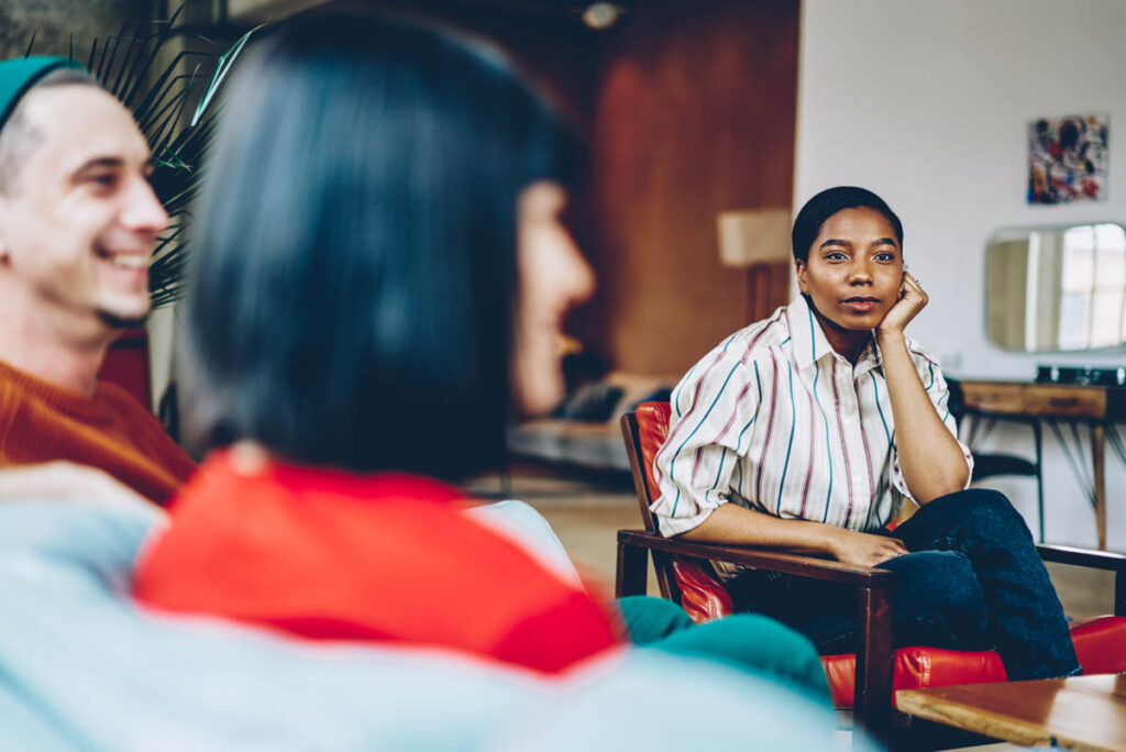 a woman sits and listens to another group member discuss their transition from treatment program to sober living